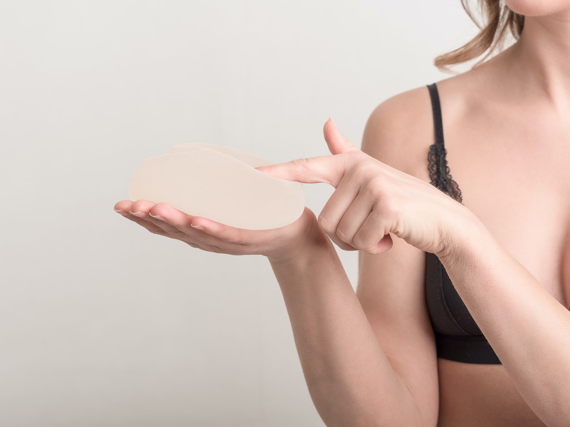 Woman holding a breast implant and feeling it in her hands